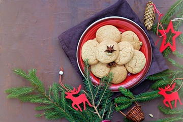 Homemade sugar cookies with cardamom in the New Year and Christmas style on the red clay plate on a brown background concrete. Copyspace.