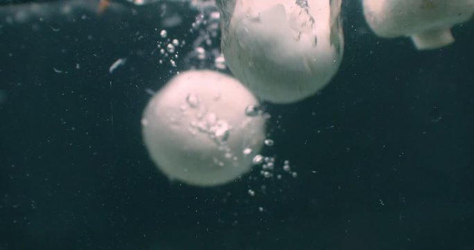 Champignons Mushrooms slowly falls into boiling water, slow motion close-up. Mushrooms champignons slowly falls into boiling water, slow motion close-up.