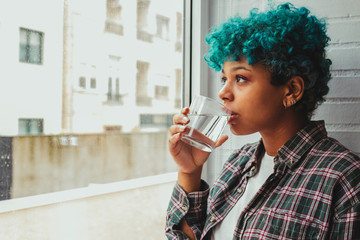 portrait of young woman or girl drinking water at home at the window
