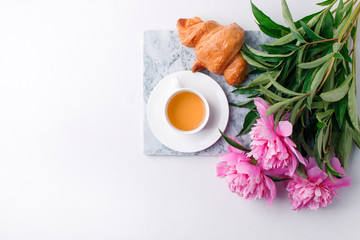 Breakfast for Valentines day with cup of tea, croissant, flowers on white table from above in flat lay style, seasonal springtime holiday background, blogger lifestyle