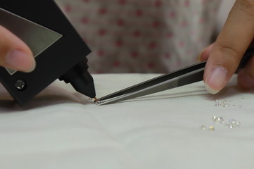 Human Hand holding Diamonds selector machine checking for real Diamond