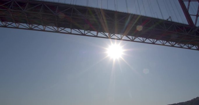 Under a huge suspension bridge with sun flares on the lens. Shot from a boat under the bridge