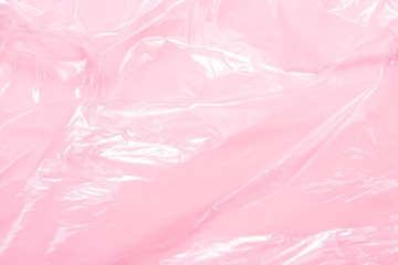 Textured,  crumpled transparent polyethylene film on pink background