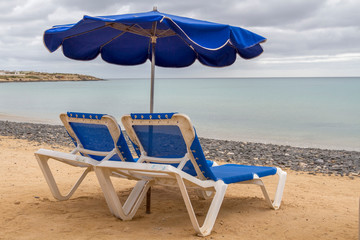 Strand mit Sonnenliegen und Sonnenschirm
