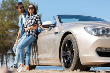 multiethnic couple standing the the car on the road, full length shot