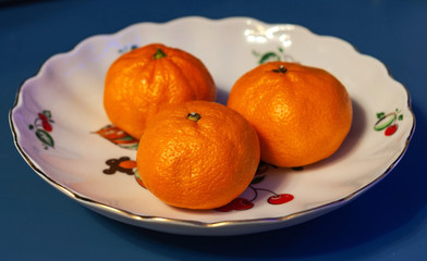 Orange tangerines on a white plate, photographed close-up