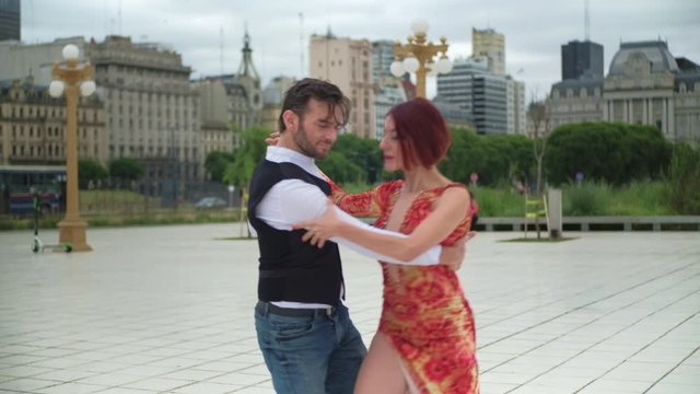 Two good looking tango dancers doing an intimate routine in a square of Puerto Madero, Buenos Aires