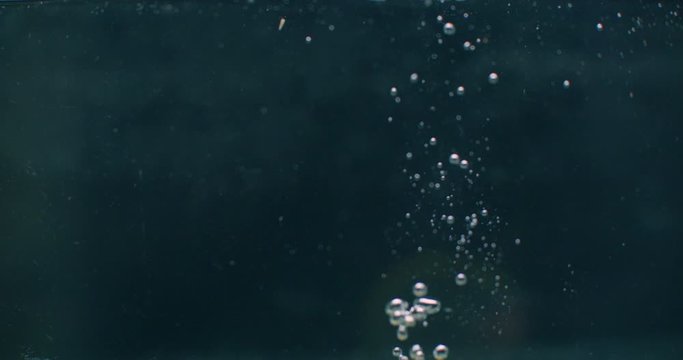 lemon falling into the water with bubbles on dark background