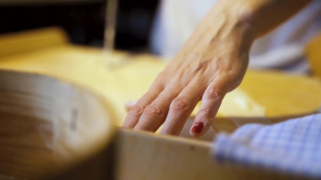 Woman with painted nails makes traditional handmade dumplings at home. Pierogi stuffed with meat, mushroom or potato stuffing. Lying dough on pastry board is sliced into similar pieces.