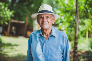 Portrait of smiling beautiful older male farmer. Elderly man at farm in summer day. Gardening activity. Brazilian elderly man. - Powered by Adobe