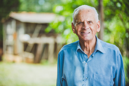 Portrait Of Smiling Beautiful Older Male Farmer. Elderly Man At Farm In Summer Day. Gardening Activity. Brazilian Elderly Man.