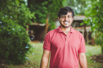 Portrait of smiling beautiful young male farmer. Man at farm in summer day. Gardening activity. Brazilian man.
