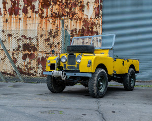 classic offroader in front of rusty building