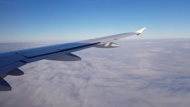 Ausblick aus fliegendem Flugzeug rechts mit Flügel oberhalb geschlossener Wolken