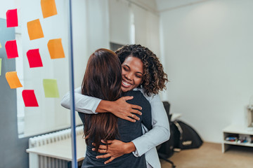 Two happy business women hugging.
