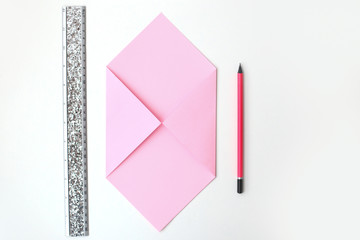 Flat lay: pink paper folded in the shape of envelop, pencil, silver ruler. Making a postcard in an envelope for Valentine's Day. Do it yourself. Photo from the series.