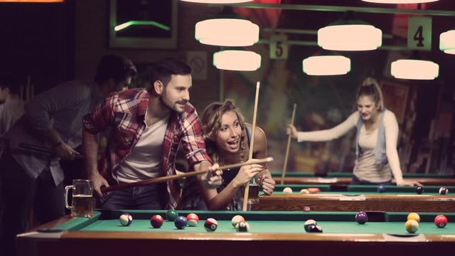 happy young people enjoying billiard game together