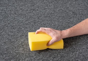 man hand without gloves cleaning gray  carpet with yellow sponge. dry cleaning technique - 312245535