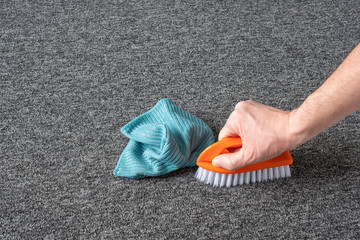 man hand without gloves cleaning gray  carpet with brush and microfibre cloth. dry cleaning technique - 312245561