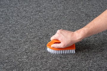 man hand without gloves cleaning gray  carpet with brush and microfibre cloth. dry cleaning technique - 312245702
