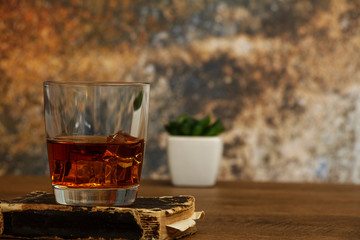 Whiskey with ice or brandy in a glass and a square carafe on an old wooden background. Whiskey with ice in a glass. Whiskey or cognac. Selective focus.