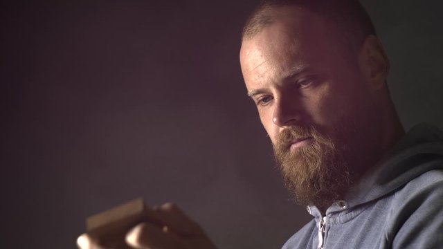a bearded carpenter examines a piece of wood