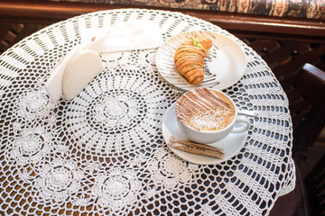Chocolate croissant with coffee and coconut powder. Tasty and fresh food.