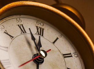 Golden vintage alarm clock showing five to twelve