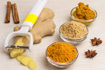 Fototapeta na wymiar Spice set: ginger root and vegetable cutter, ginger and turmeric powder, turmeric paste on a light background