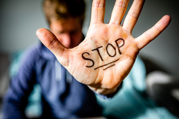 Man holds hand to camera with STOP written on palm.