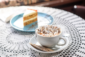 Carrot cake and marshmallow cappuccino on the table in a cozy chocolate bowl. Tasty and satisfying.