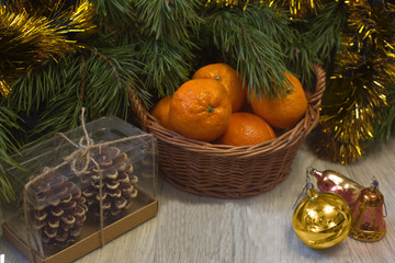 Christmas card. A basket of tangerines and holiday decorations on the table, next to a Christmas tree.