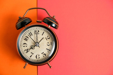 Old, vintage retro alarm clock on orange red background.