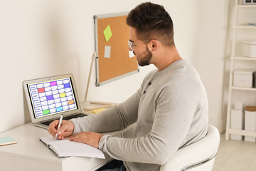 Obraz na płótnie Canvas Young man using calendar app on laptop in office