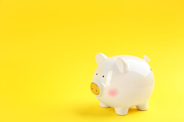White piggy bank on yellow background. Space for text