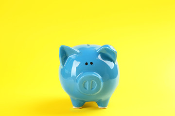 Cute blue piggy bank on yellow background