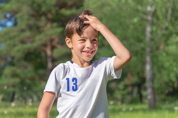 Naklejka premium smiling boy in a white t-shirt on a background of nature. concept of childhood and summer holidays
