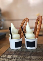 Selective focus of a churro is a fried-dough pastry with milk icecream in paper cup.