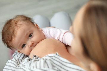 Young woman breastfeeding her baby at home, closeup