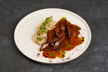 Baked lamb tongues with spicy bulgur porridge in a white plate