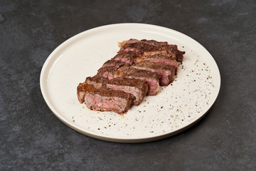 Grilled beef steak with spices on a white tray, close-up