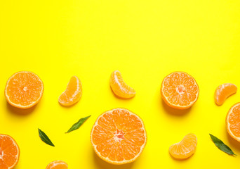 Flat lay composition with halves of fresh ripe tangerines and leaves on yellow background, space...