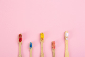 Toothbrushes made of bamboo on pink background, flat lay. Space for text