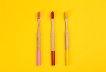 Toothbrushes made of bamboo on yellow background, flat lay. Space for text