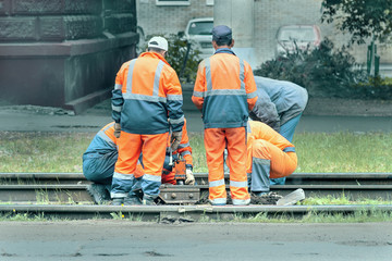railway workers in orange uniform repair tracks