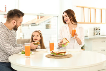 Obraz na płótnie Canvas Happy family having breakfast with sandwiches at table in kitchen