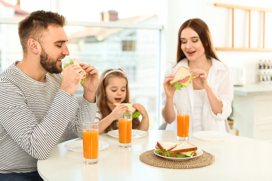 Happy Family Having Breakfast With Sandwiches At Table In Kitchen