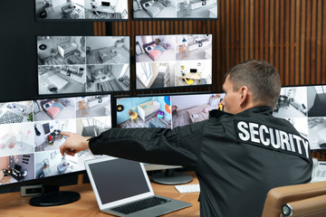 Fototapeta na wymiar Security guard with portable transmitter monitoring modern CCTV cameras indoors