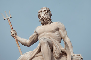 The mighty god of the sea and oceans Neptune (Poseidon) The ancient statue against blue sky.