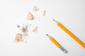 Graphite pencils and shavings on white background, top view